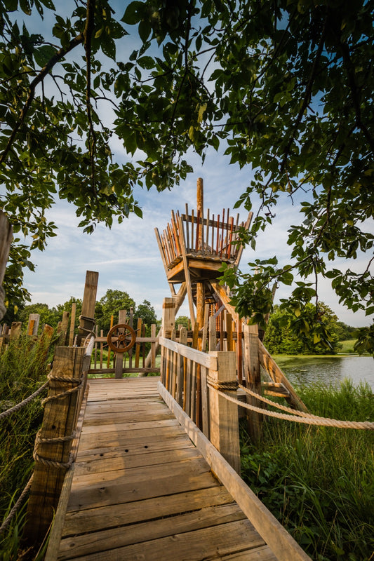 Wooden rope-lined adventure boardwalk leading to treehouse tower beside lake at Powell Gardens near Kansas City Missouri