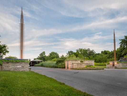 Powell Gardens entrance with tall metal spire sculptures and stone walls under dramatic sky near Kansas City Missouri