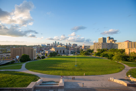 Wide view of the Liberty Memorial grounds with expansive green lawn Union Station and the full Kansas City skyline under blue sky